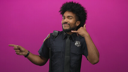 Police officer pointing and smiling against vibrant pink background, with short afro and uniform...