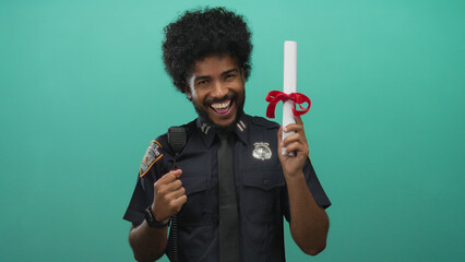 Police officer wearing uniform celebrating with diploma against green wall background showcasing...