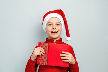 Cheerful boy in Santa hat holding an envelope, postcard, greeting, letter to Santa Claus ,...