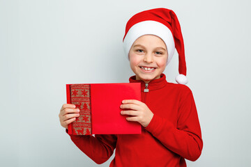 Cheerful boy in Santa hat holding an envelope, postcard, greeting, letter to Santa Claus ,...