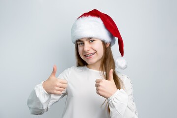 Cheerful little girl in Santa hat showing joy, delight, surprise, approval. Happy emotions, joy of...