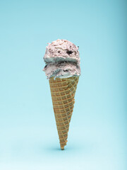 Cookies and cream ice cream cone, isolated on a light blue background