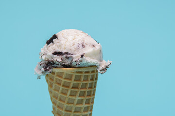 Cookies and cream ice cream cone, isolated on a light blue background
