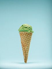 Green mint ice cream cone, isolated on a pale blue background