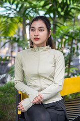 Beautiful asian woman sitting in the park to rest after exercise. Women relax and enjoy the...