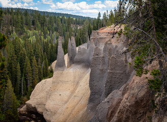 The Pinnacles at Crater Lake National Park stand prominently against a backdrop of dense evergreen...