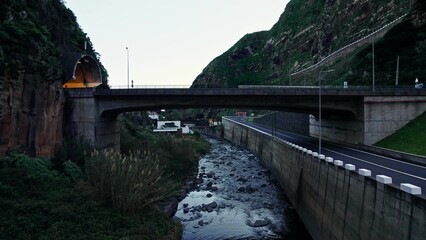 Fototapeta premium The drone is flying over a mountain river between rocks. It flies under pedestrian bridges