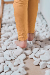 Vertical shot of todler walking on the stones for the flat foot correction in clinic. Feet close-up...