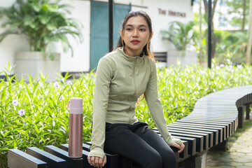 Asian woman sitting in the park to rest after exercise. Fitness athlete woman resting after...