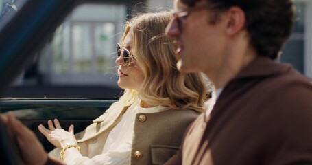 Stylish man and woman get out of a retro car after a trip on a sunny day