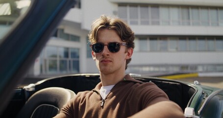 Portrait of a man in a convertible. A man in sunglasses looks at the camera with a serious look...