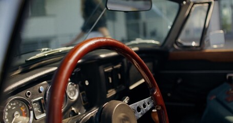 A woman puts her hand on the steering wheel of a retro car, preparing for a trip. Close-up of her...