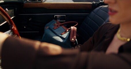 A woman drives a retro car. Close-up of her bag in the passenger seat