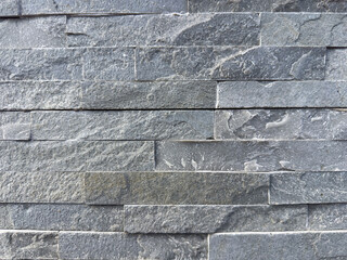 Close-up of textured gray stone wall with rough surface and stacked pattern