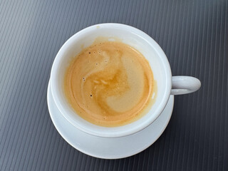 White cup of fresh espresso on black table surface