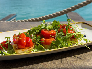 Fresh bruschetta with arugula and cherry tomatoes by the sea