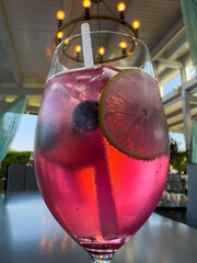 Refreshing pink cocktail with lime and berries in elegant glass at outdoor bistro