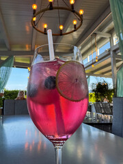 Refreshing pink cocktail in outdoor cafe with lime and blueberries