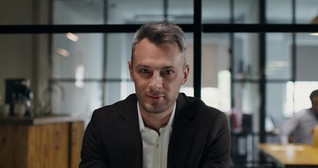 Portrait of a man sitting at a desk in an office. Close-up of his smiling face