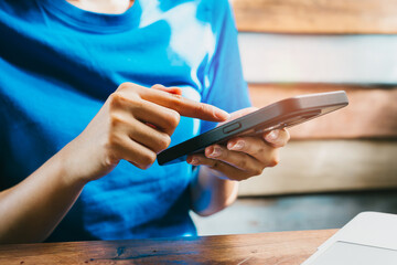 Woman using smartphone. Person in Blue Shirt Interacting with Smartphone at Wooden Table Surrounded...