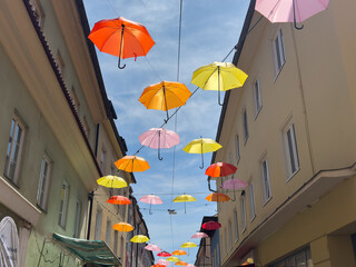 Villach, Austria - July 01, 2025: Colorful umbrellas suspended above a charming street in a vibrant...