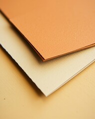 Close-up shot of layered sheets of textured paper, displaying shades of orange and beige.