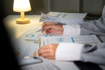 Late Night Analysis. A woman reviewing charts and graphs while working late.