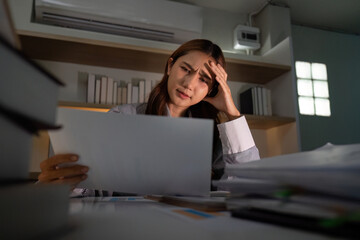 Late Night Stress. Young woman feeling overwhelmed while reviewing documents.