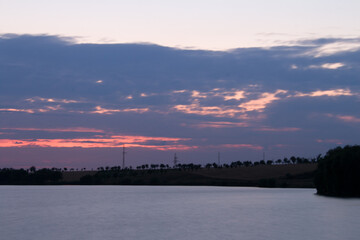 A body of water with trees and a cloudy sky