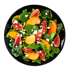 Salad of peaches, figs, arugula, spinach and goat cheese on a black plate. Above view isolated on a white background.