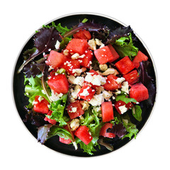 Salad of watermelon, lettuce and feta cheese on a black plate. Top view isolated on a white background.