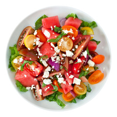 Salad of watermelon, cherry tomatoes, lettuce and goat cheese on a white plate. Overhead view isolated on a white background.