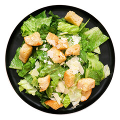 Classic caesar salad on a black plate. Top down view isolated on a white background.