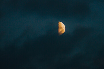 Growing moon in dark cloudy evening sky. Dark colors of summer night.

