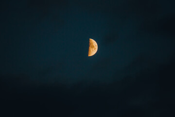 Growing moon in dark cloudy evening sky. Dark colors of summer night.
