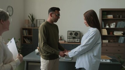 Happy biracial couple gently embracing reuniting after relationship crisis then gratifying female psychotherapist for help in office - Powered by Adobe