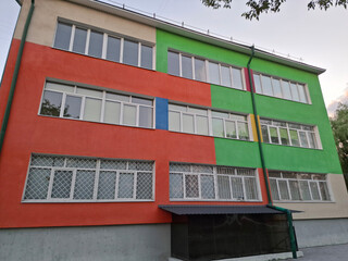School building with many-coloured wall and windows with metal bars
