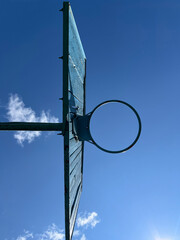 Basketball hoop silhouette against blue sky with white clouds background Basketball hoop mounted on...