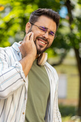 Portrait of young Caucasian man standing outdoors feeling toothache bad unpleasant symptoms...