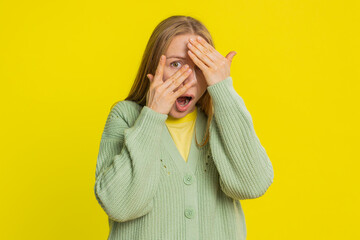 Nosy curious Caucasian middle-aged mature woman closing eyes with hand and spying through fingers,...