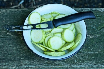 one iron shiny special kitchen knife with black plastic handle lies on cut pieces of fresh green...