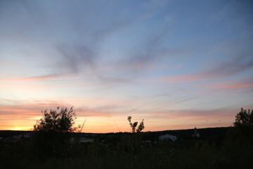 Beautiful sunset sky and tree silhouette under bright colorful clouds from the high. Yellow orange...