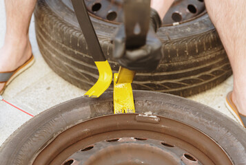 A young man uses a crowbar to disassemble a car tire.