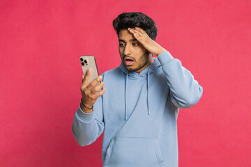 Upset sad Indian man use smartphone typing browsing, play game, loses, surprised by sudden lottery...