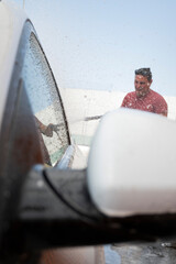 Car wash employee spraying foam on a car window