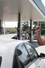 Man washing white car with pressurized water at service station