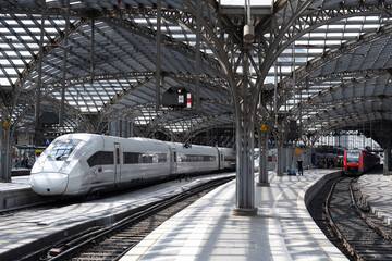 A historic train station in the German city of Cologne, with trains, industrial architecture and a...