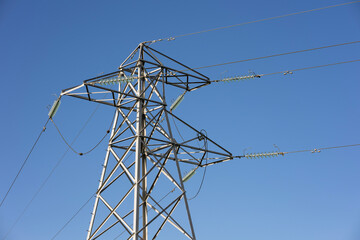 High Voltage Electricity Pylon with Cables and Glass Insulators Against Blue Sky