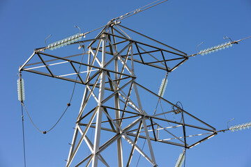High Voltage Electricity Pylon with Cables and Glass Insulators Against Blue Sky