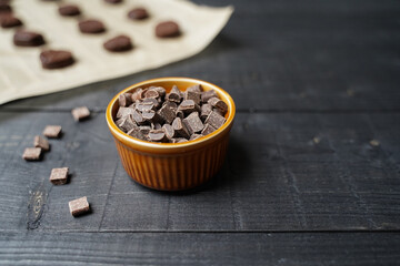 Front view of chocolate chip cookie dough on baking paper with brown bowl of chocolate chips on...